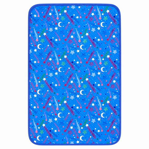 A rectangular blue mat or pad with rounded corners, featuring an all-over space-themed print of stars, crescent moons, shooting stars, and dots in multiple colors, shown on a plain white background.