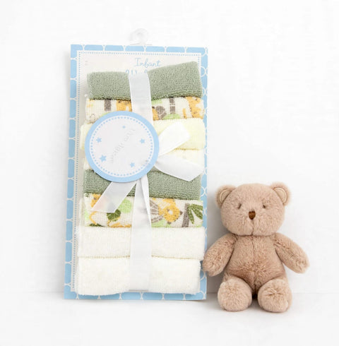 A baby gift set featuring a packaged set of folded cotton towels and a small plush teddy bear on a white background. The towels are in soft pastel shades of green, yellow, and white, some with delicate floral prints.