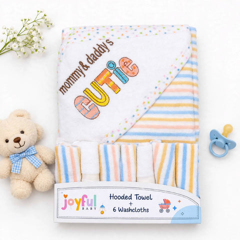 A folded baby hooded towel set with six washcloths, featuring pastel striped patterns and embroidered text reading 'mommy & daddy's CUTIE' on a white hood. The set is displayed on a white background with a small teddy bear, baby flowers, and a pacifier as props.