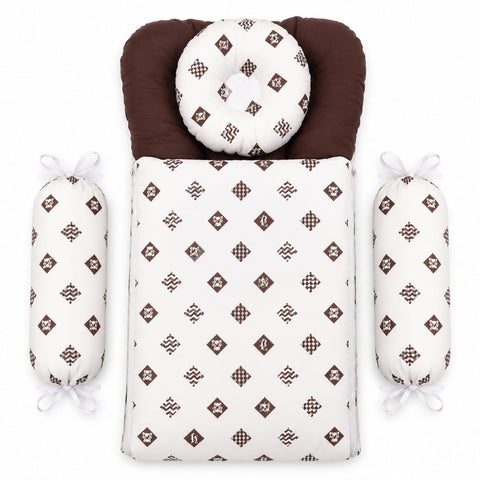 A baby bedding set laid flat on a white background, including a rectangular bassinet cover with a brown and white geometric pattern, a matching round head pillow, a dark brown padded neck insert, and two cylindrical side protectors tied with white ribbons.