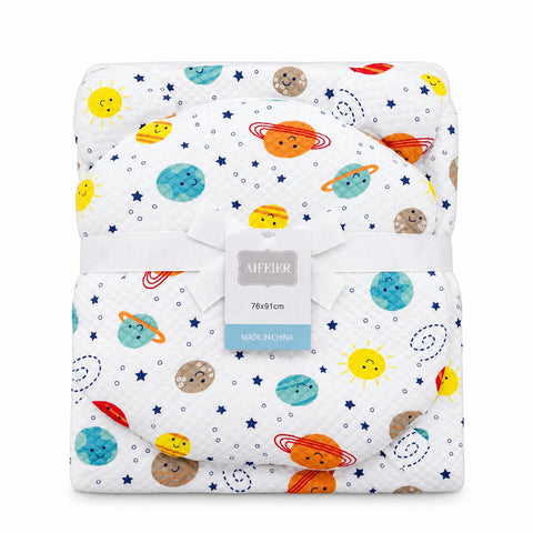 A folded baby blanket with a white background and a colorful space-themed print featuring cartoon planets, stars, and suns. A white ribbon bow and a central paper tag are wrapped around the blanket, which is photographed on a clean white background.