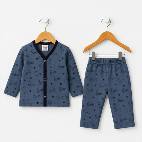 A two-piece baby clothing set consisting of a long-sleeve cardigan and matching pants, both in a dusty blue color with an all-over 'love' script pattern. The cardigan features a black V-neck trim and snap-button closure, and is displayed on a wooden hanger next to the matching pants on a white background.
