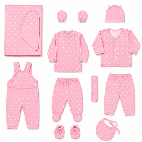 A baby clothing set arranged on a white background, including a pink long-sleeve top, matching pants, cardigan, overalls, booties, bib, hat, swaddle, and a small remote control, all in a light pink fabric with small white polka dots.