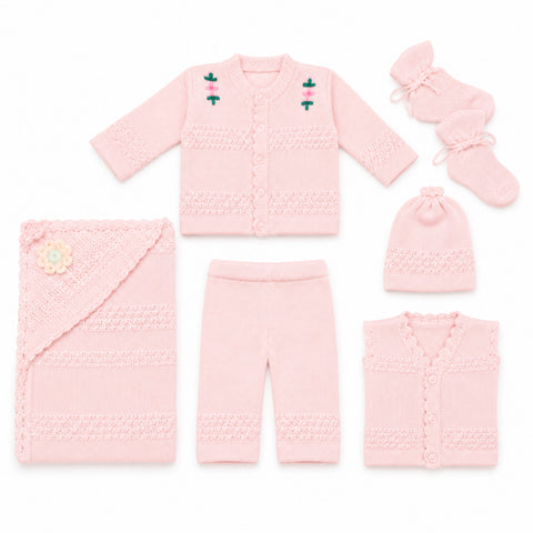 A coordinated baby knit clothing set laid out on a white background, including a long-sleeve cardigan, pants, a hat, a sleeveless vest, a swaddle wrap, and booties. The set is light pink with textured knit patterns and small embroidered floral details on the cardigan.