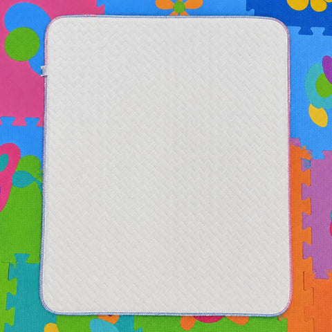 A square white textured mat with rounded corners and a stitched border, laid flat on a colorful children's foam play mat.