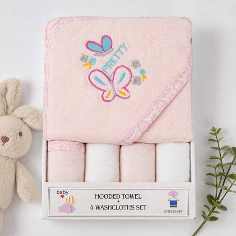 A boxed baby towel set on a white background, featuring a folded pink hooded towel with embroidered butterfly and 'PRETTY' design, plus four rolled washcloths underneath in matching pale pink and white. A plush bunny is partially visible on the left and a green sprig on the right.