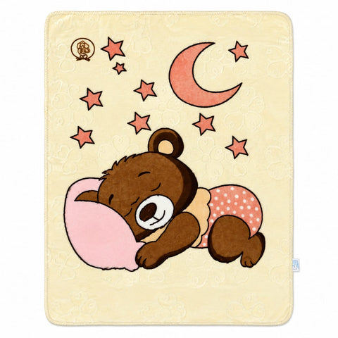 A square cream-colored blanket featuring a cartoon sleeping brown bear wearing pink polka-dot pajamas, next to a pink pillow, with a pink crescent moon and pink stars in the background.