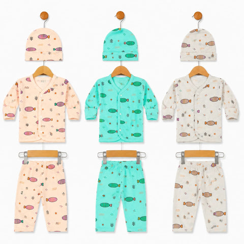 Three baby clothing sets displayed on wooden hangers against a white background, each set including a hat and matching pants. The left set is light peach with pink fish prints, the center set is mint green with green fish prints, and the right set is cream with orange fish prints.