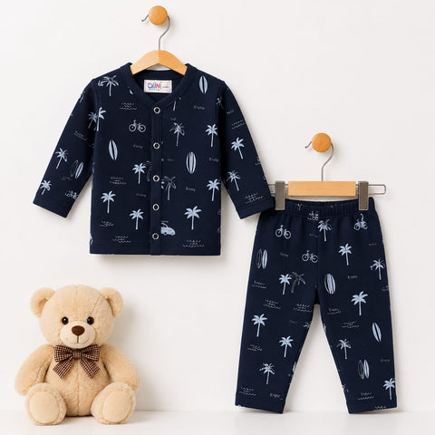 A two-piece baby clothing set consisting of a long-sleeve button-front cardigan and matching pants, both in navy blue with a white palm tree, bicycle, and surfboard print. The set is displayed on wooden hangers against a white wall, with a plush teddy bear positioned in the lower-left corner.