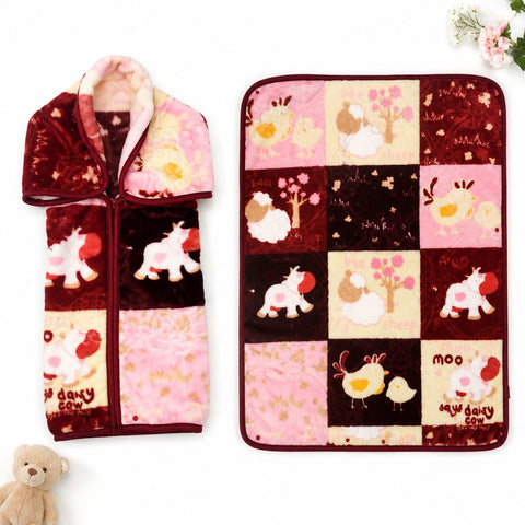 A plush fleece blanket with a patchwork design featuring cartoon animals and trees in pink, burgundy, and cream, shown both flat and folded with a zipper pocket on the front. A small teddy bear is at the bottom left, and flowers are at the top right, on a white background.