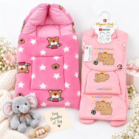 A baby gift set featuring a pink hooded fleece sleeper with teddy bear and star prints, a matching pink 3-piece outfit set with a bonnet and bib, a small gray plush elephant toy, and a wooden teething ring on a white background.