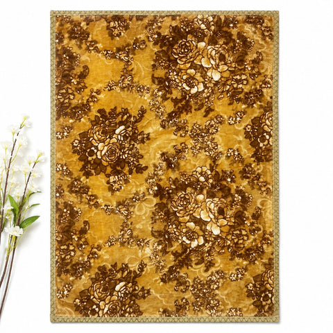 A rectangular area rug with an ornate floral damask pattern in golden yellow and dark brown, shown flat against a white background with a small decorative floral sprig on the left.