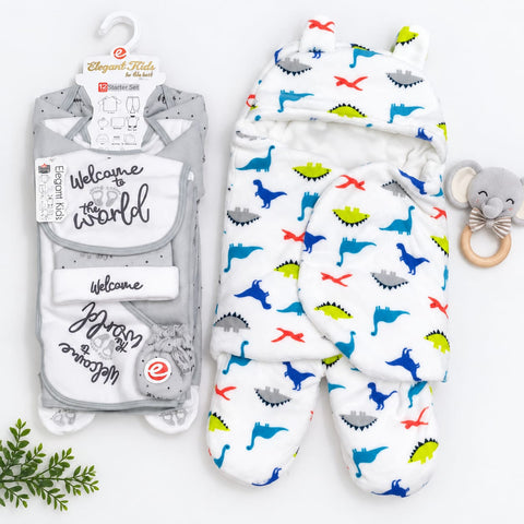 Two baby sleepers and a matching pacifier set arranged on a white background. One sleeper is in packaging with a gray and white design featuring 'Welcome to the world' text and a bear graphic; the other sleeper is white with a colorful dinosaur print in blue, green, red, and gray.