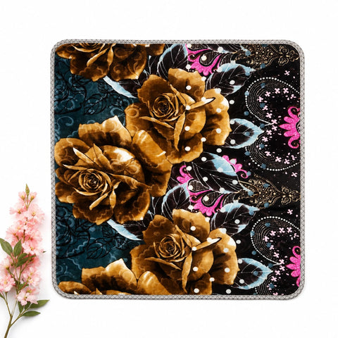 A square decorative mouse pad with a detailed floral and paisley pattern, featuring large gold and brown roses on a black background with teal and pink accents, shown on a white surface with a small pink flower prop in the corner.