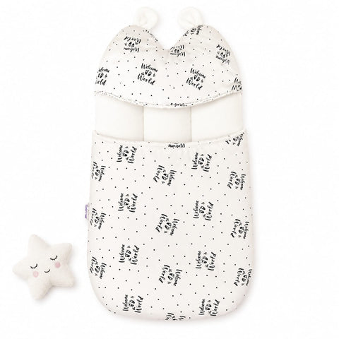 A baby sleep bag or swaddle in warm off-white fabric with a black hand-lettered 'Happy Birthday' print and small black dots, shown on a white background with a matching plush star toy.