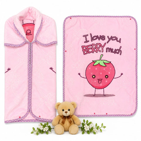 A pink baby blanket and matching pink swaddle wrap set, displayed on a white background with a small teddy bear and white flowers as props. The blanket features a cute cartoon strawberry character and the text 'I love you BERRY much'.