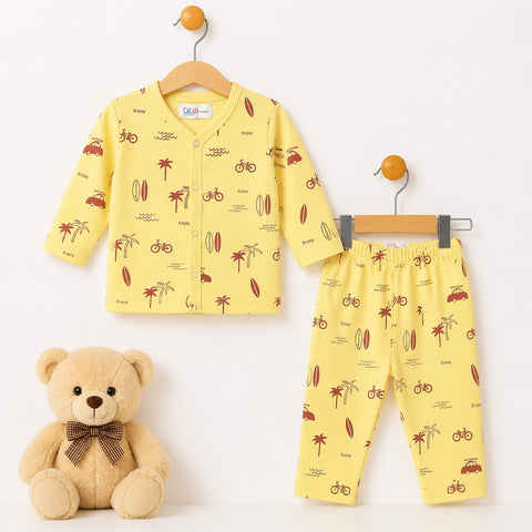 A baby two-piece clothing set consisting of a long-sleeve cardigan and matching pants in yellow, both printed with brown palm trees, bicycles, and surfboards. The set is displayed on wooden hangers next to a plush teddy bear on a plain white background.