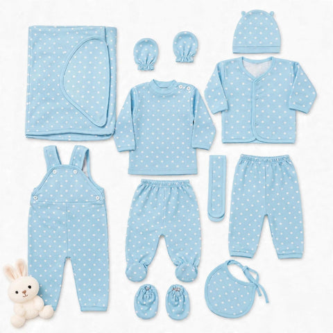 A baby clothing set laid out on a white background, including a light blue long-sleeve top, matching pants, cardigan, hat, bib, booties, overalls, mittens, and a blanket, all with a white polka dot pattern. A small plush bunny is placed at the lower left.