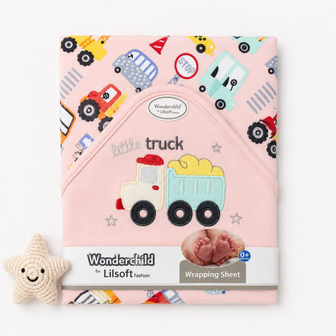 A pink Wonderchild by Lilsoft wrapping sheet for a baby bonnet, featuring an embroidered truck design and a playful multicolor vehicle print. A small beige knitted star toy is placed to the left on a clean white background.