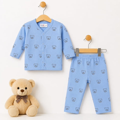 A baby two-piece outfit set consisting of a light blue long-sleeve button-front cardigan and matching pants, both printed with a small bear face pattern. The set is displayed on wooden hangers against a white background, with a plush teddy bear wearing a bow tie sitting on the bottom left.