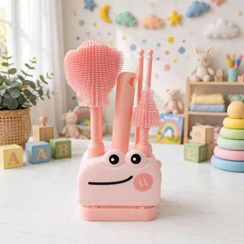 A pink children's cleaning brush set with a smiling pig-shaped holder, shown on a white tabletop in a softly styled nursery-like room with toys and wall decorations in the background.