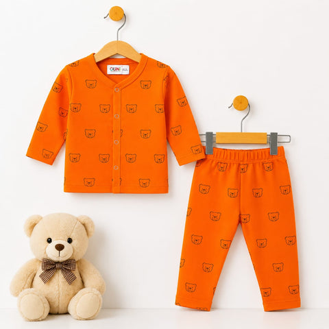A baby two-piece outfit set consisting of an orange long-sleeve cardigan and matching pants, both printed with a small teddy bear face pattern. The cardigan is shown on a wooden hanger, the pants on a gray hanger, and a plush teddy bear sits on the floor below against a clean white background.