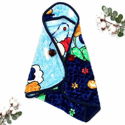 A quilted baby wrap or blanket with a colorful cartoon animal print, featuring a light blue side with a white rabbit and a dark navy side with a frog, styled flat-lay on a white background with cotton stems.