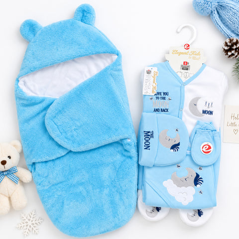 A baby gift set featuring a plush light blue hooded swaddle wrap and a matching clothing set on a white background with styled props including a teddy bear, snowflake, pine cone, and blue knit hat.