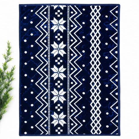 A rectangular area rug with a Nordic-style geometric pattern in navy blue and white, shown flat on a white background with a small green plant on the left side.