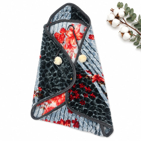 A plush fleece baby wrap or swaddle blanket with a black and red floral print, featuring a textured black chevron pattern on one side and a red floral print on a light blue-gray background on the other. It is styled on a white background with a decorative cotton sprig in the top right corner.