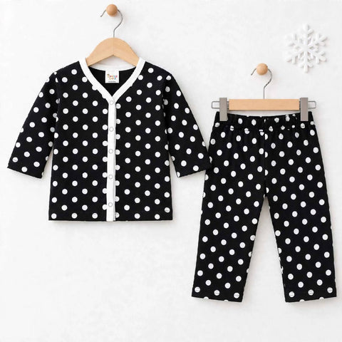 A baby clothing set consisting of a long-sleeve cardigan and matching pants, both in black with white polka dots. The cardigan has a white V-neck trim and button closure, hanging on a wooden hanger.