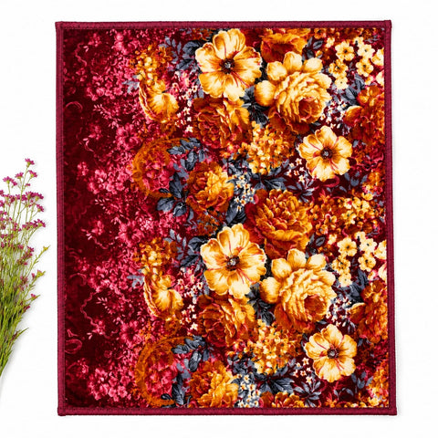 A square textile product, likely a scarf or small blanket, featuring a dense floral pattern with prominent orange and yellow flowers, deep red background areas, and dark blue-gray leaves. The textile is laid flat against a white background with a small decorative plant stem on the left edge.