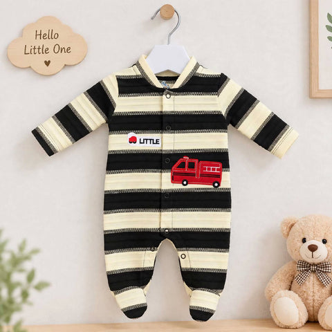 A baby long-sleeve footed sleeper with black and cream horizontal stripes, featuring a red fire truck graphic and 'LITTLE' text on the chest, hanging on a wooden hanger against a light wall with a teddy bear and decorative cloud sign nearby.