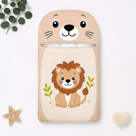 A children's sleep sack or blanket featuring a cute cartoon lion on the front and a matching lion-face hood, shown in a styled flat-lay with eucalyptus leaves, a star, and a small heart on a white background.