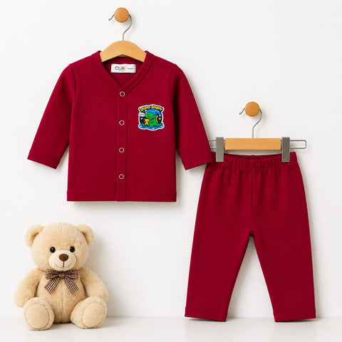 A two-piece baby outfit set consisting of a long-sleeve red cardigan and matching red pants, displayed on wooden hangers next to a beige teddy bear. The cardigan features a colorful dinosaur patch on the left chest.