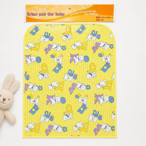 A baby urine pad package shown on a white background, with a small plush bunny partially visible at the lower left. The pad is yellow with a grid pattern and an allover cartoon print in blue, purple, and white.