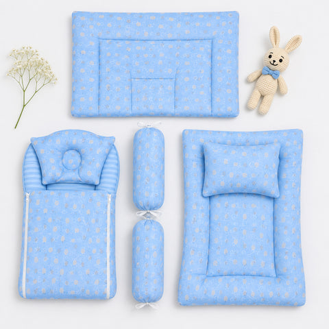 A coordinated baby bedding set arranged on a white background, including a rectangular mat with a bunny motif, a padded cushion, a striped pillow cover, two cylindrical bolsters, and a padded floor mat with a matching pillow. A small knitted bunny toy and a sprig of baby's breath are placed beside the items.