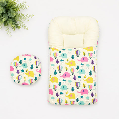 A baby travel seat cover and matching footmuff set with a colorful elephant and tree pattern on a cream background, displayed on a white surface with a green plant in the corner.