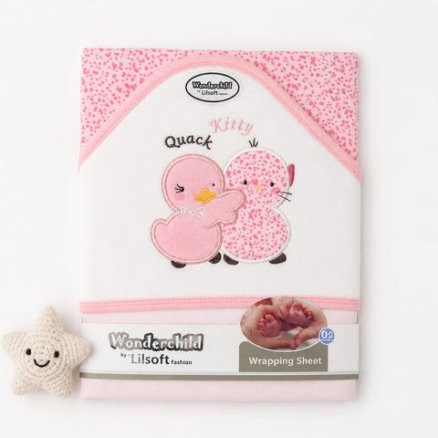 A personalized baby wrapping sheet by Wonderchild by Lilsoft, featuring a pink and white spotted pattern with embroidered pink ducks and the text 'Kitty Quack'. A small cream-colored crocheted star toy is placed to the left on a clean white background.