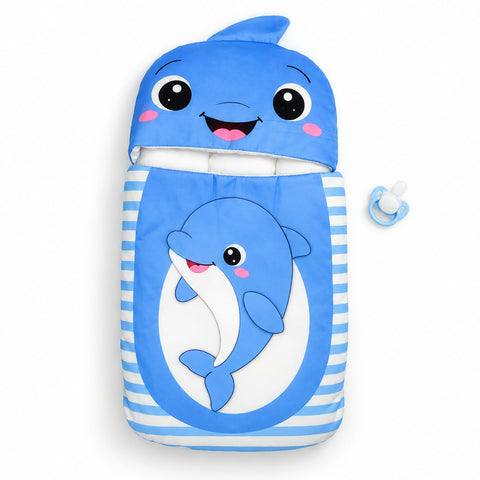 A blue and white baby sleep bag or swaddle with a hood shaped like a smiling whale face, featuring a large dolphin illustration on the front. A matching blue pacifier is placed to the right on a plain white background.