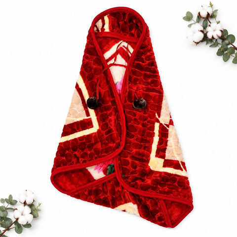 A folded red plush blanket or throw with a textured crocodile pattern and cream geometric accents, styled on a white background with decorative cotton and eucalyptus sprigs.