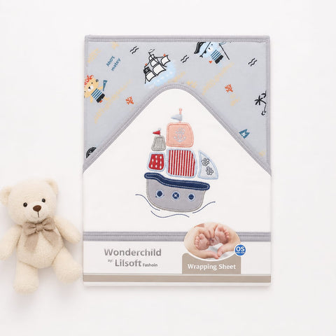 A baby wrapping sheet with a nautical theme, displayed next to a small cream teddy bear. The sheet features a light gray top section with embroidered ships, waves, and stars, and a white bottom section with a large embroidered ship design.