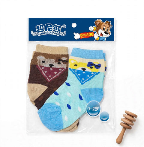 A pair of children's knit socks in a clear plastic package with a blue header card. One sock is brown with a tan bear face and red bandana pattern, and the other is light blue with darker blue spots and a blue/yellow bandana pattern.