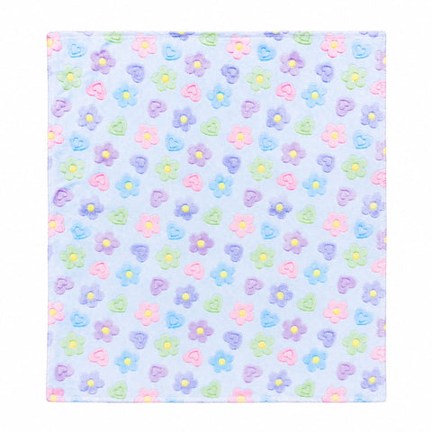 A square fabric item, likely a napkin or small cloth square, featuring a repeating pattern of small felt flowers in pastel pink, purple, blue, and green on a light blue background.