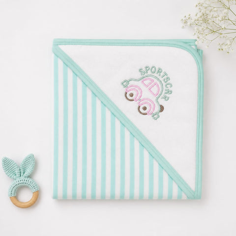 A folded baby hooded towel with mint green and white vertical stripes on one side and a solid mint green border, featuring an embroidered pink sports car and the words 'SPORTSCAR' on the corner. A small mint and wooden teething ring is placed to the left on a white background with baby flowers in the top right corner.