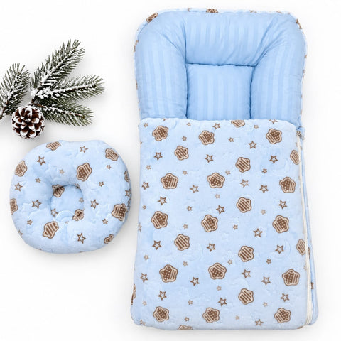 A baby sleep bag and matching footmuff set in light blue, decorated with a pattern of brown cupcakes and stars. The set is displayed on a clean white background with a decorative pine branch and pinecone in the top-left corner.
