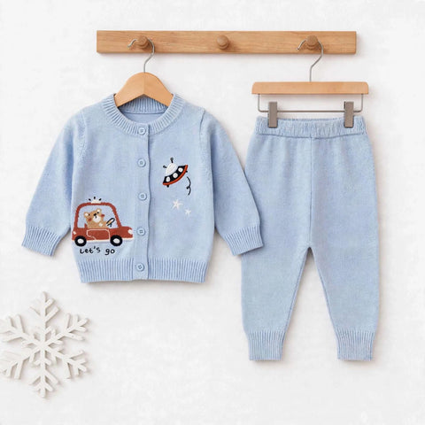 A baby knit two-piece outfit set consisting of a light blue cardigan sweater and matching pants, hanging on wooden hangers against a white textured background. The cardigan features cartoon embroidery of a red car with a dog and a red rocket ship.