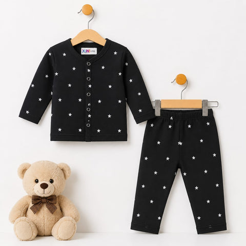 A baby clothing set consisting of a black long-sleeve cardigan top and matching pants, both decorated with small white star patterns. The set is displayed on wooden hangers next to a beige teddy bear toy on a plain white background.